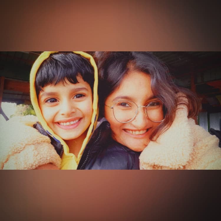 Vyom in a cozy yellow hoodie beaming with a radiant, joyful smile